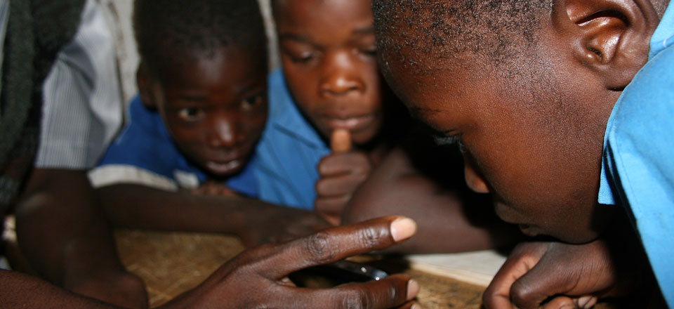 Several Malawian boys using a handheld player